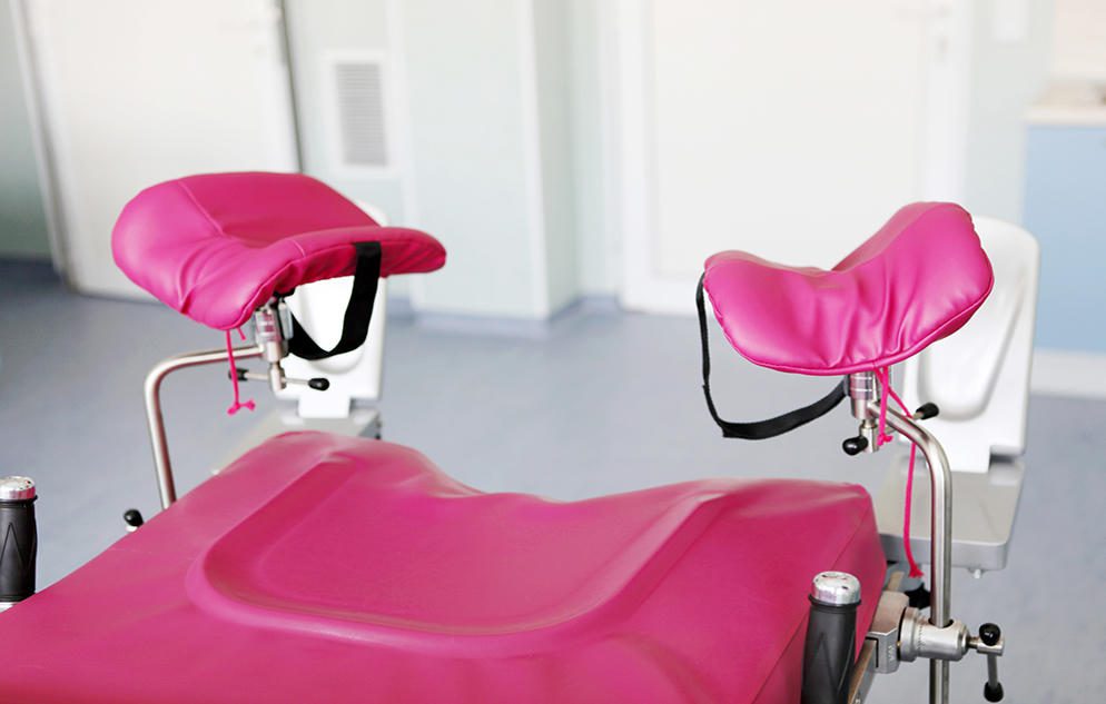 Pink medical examination chair with stirrups.