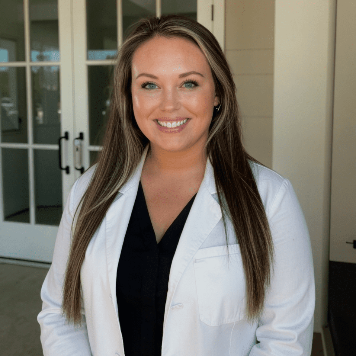 Smiling woman in white coat indoors.