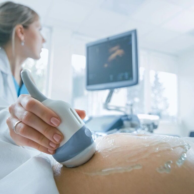 Ultrasound examination of pregnant woman's abdomen.